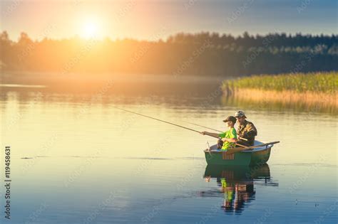 Father And Son Catch Fish From A Boat At Sunset Stock Photo Adobe Stock