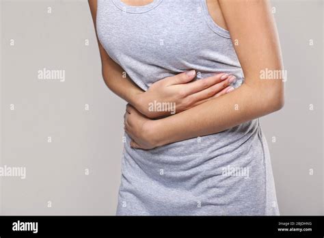Close Up View Of Woman Suffering From Abdominal Pain On Grey Background