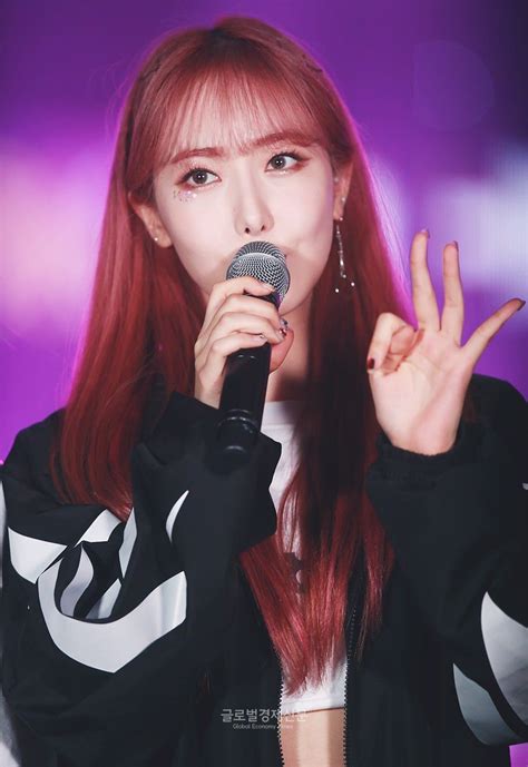 a woman with red hair holding a microphone in front of her face and making the peace sign