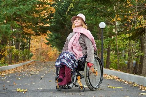 Handicapped Paralyzed Smiling Woman In A Wheelchair Moves In The Autumn