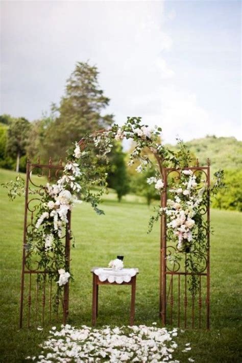 An Outdoor Ceremony Setup With White Flowers And Greenery On The Grass