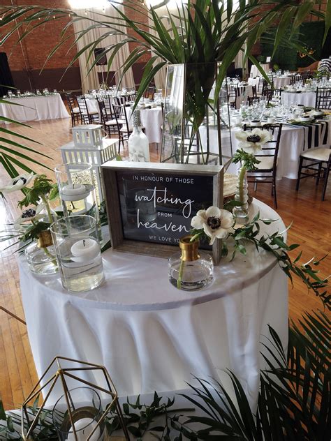 The Table Is Set Up With White Flowers And Greenery For An Elegant