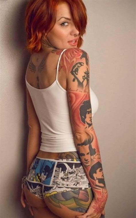 A Woman With Red Hair And Tattoos On Her Body Is Leaning Against A Wall