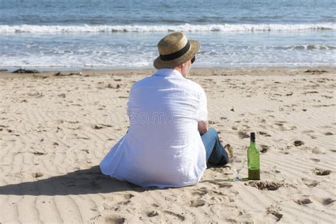 Mature Man Resting With Wine On The Beach In Summer Stock Photo