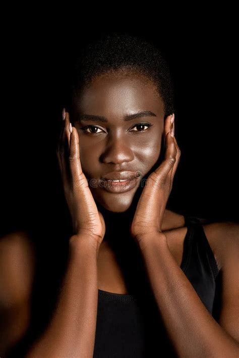 portrait of beautiful african american woman touching face with hands and smiling at camera