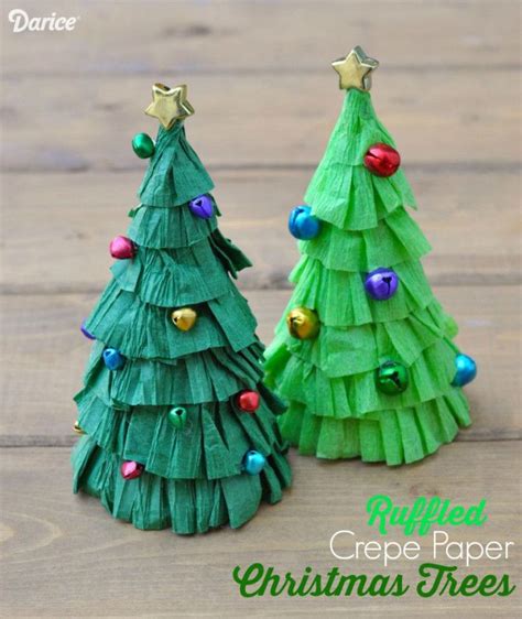 Two Christmas Trees Made Out Of Paper On Top Of A Wooden Table With