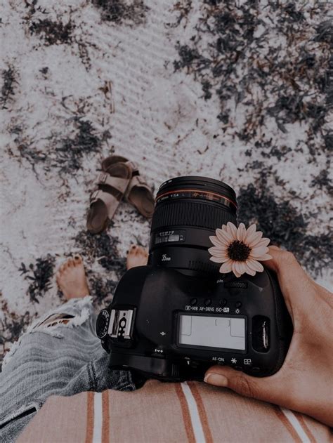 A Person Holding Up A Camera With A Flower On Its Body And Feet