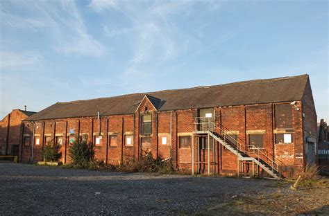 An Old Abandoned Brick Factory Building With Boarded Up Windows And
