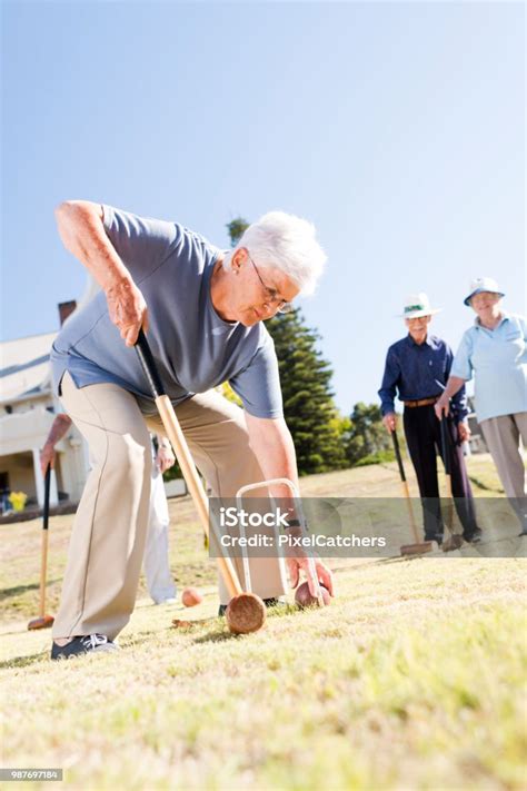 Senior Woman Bending Down Picking Up The Croquet Ball Stock Photo