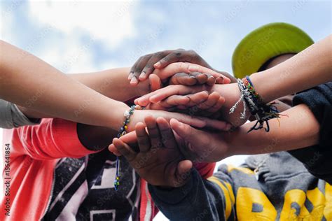 Multiracial Teenagers Joining Hands Together In Cooperation Stock Photo