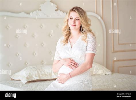 Attractive Pregnant Woman Is Sitting In Bed And Holding Her Belly Last