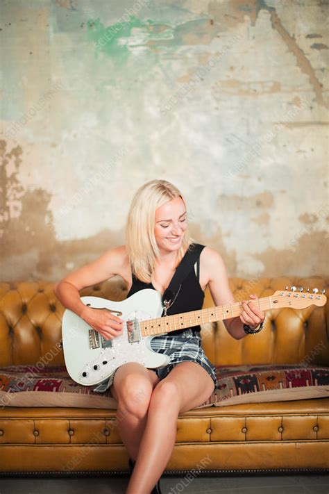 Young Woman Playing Electric Guitar On Sofa Stock Image F0239017