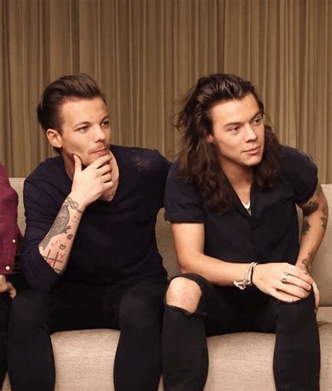 Two Men Sitting On A Couch Next To Each Other With Their Hands In Their Pockets