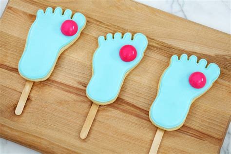 Three Cookies Shaped Like Feet With Blue Icing And Red Balls On Them