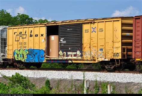 A Yellow Train Car With Graffiti On Its Side Sitting On The Tracks In