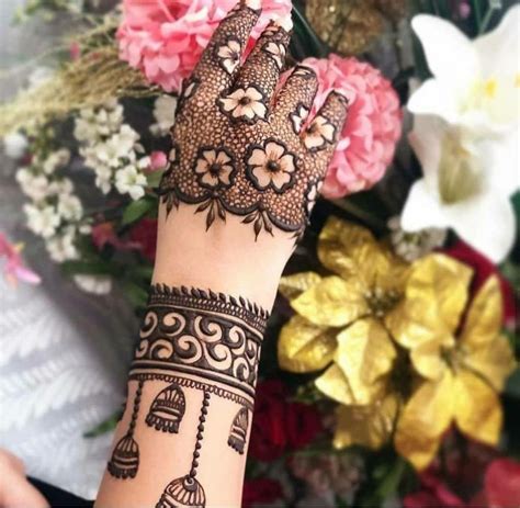 A Henna Tattoo On Someones Hand With Flowers In The Backgroud
