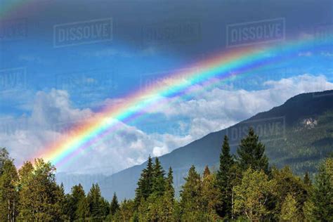 Colourful Rainbow Across The Sky With Mountain Side Storm Clouds And