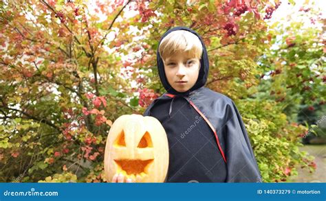 Kid In Vampire Costume Posing With Pumpkin For Camera Trick Or