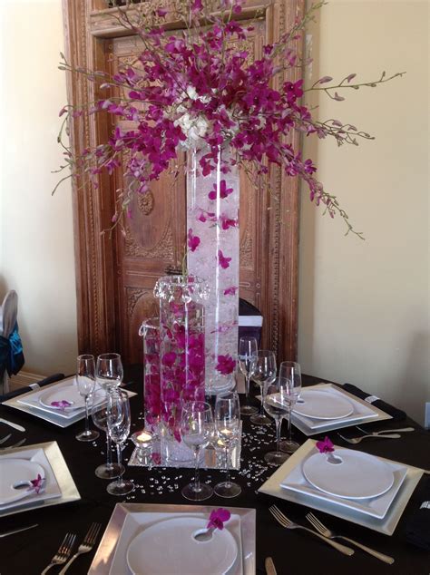 A Tall Vase Filled With Purple Flowers Sitting On Top Of A Table Next
