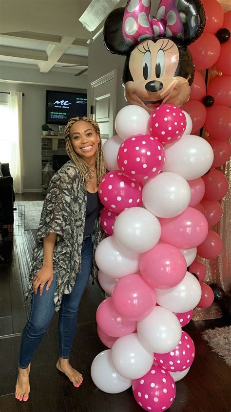 A Woman Standing Next To A Balloon Column With Minnie Mouse Balloons