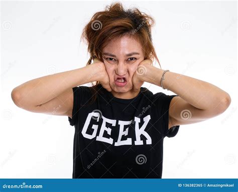 Studio Shot Of Young Asian Geek Girl Squeezing Her Face Against Stock