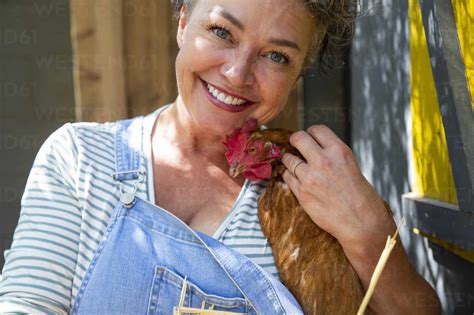 Happy Mature Poultry Farm Owner Stroking With Hen Stock Photo