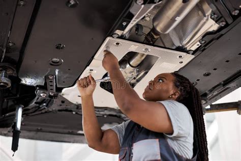 Black Female Auto Mechanic Working Underneath Car In Garage Inspecting