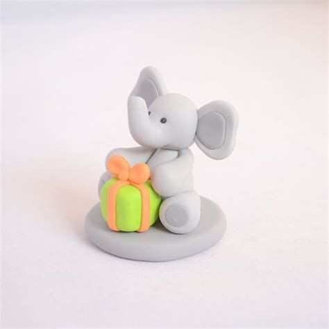 An Elephant Figurine Sitting On Top Of A Green Ball With A Bow Around