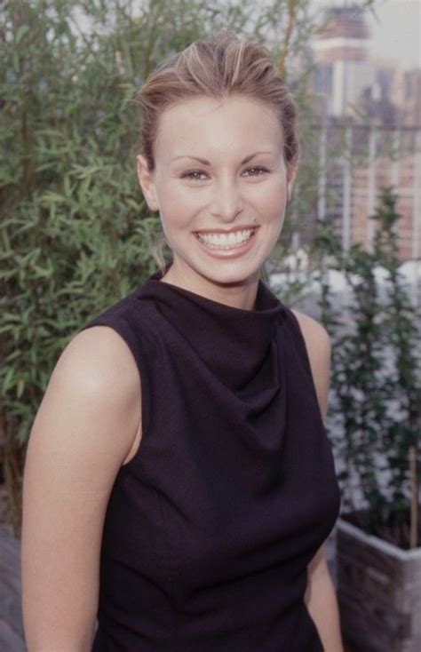 A Woman In A Black Dress Smiling At The Camera With Trees And Buildings