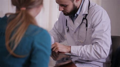 Male Doctor Writes A Prescription To His Young Female Patient And Gives