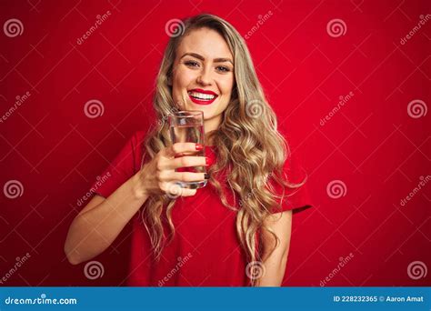 Young Beautiful Woman Drinking A Glass Of Water Over Red Isolated Background With A Happy Face