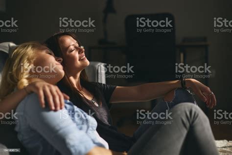 Young Happy Lesbians Couple Sitting On A Sofa And They Are Hugging
