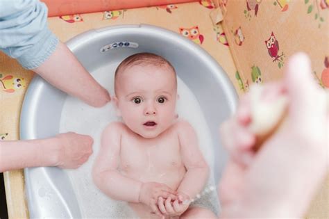 Su Padre Baña El Retrato De Un Bebé Usando La Bañera En Su Casa Foto