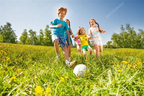 Niños jugando en la calle de un barrio suburbano. Niños felices jugando al fútbol en campo verde — Foto de stock © serrnovik #48545869