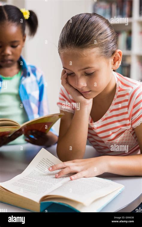 Schoolgirl Reading A Book In Library Stock Photo Alamy