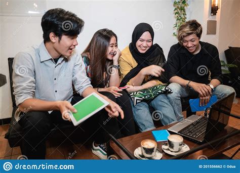 Group Of Smiling Teenagers Staying Together Using Gadget Stock Photo