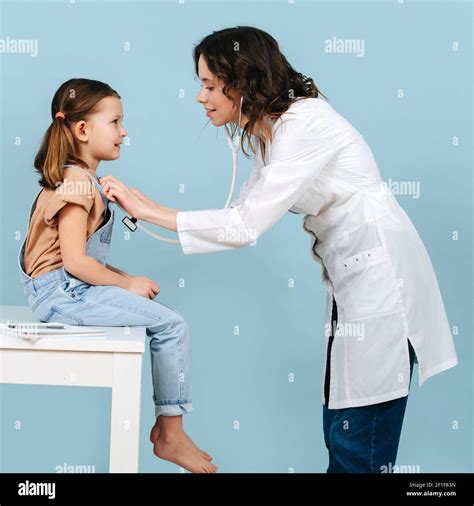 Friendly Young Female Doctor Examining Little Girl With A Stethoscope