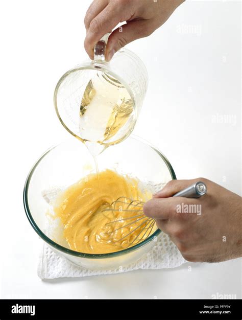 Man Whisking Egg Yoke And Dijon Mustard In Mixing Bowl With Sunflower