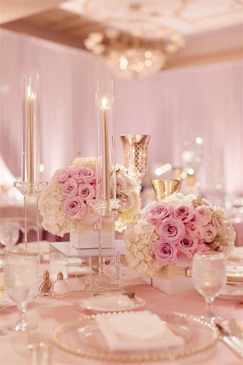 The Table Is Set With White And Pink Flowers In Vases Silverware And