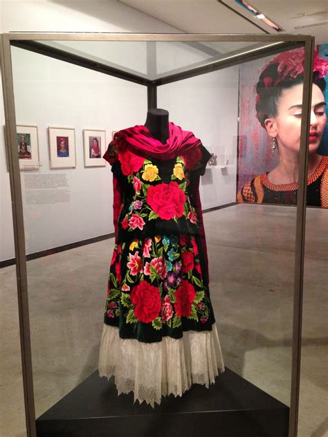 A Dress On Display In A Glass Case With Pictures Behind It And An Image