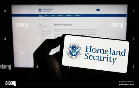 Person Holding Smartphone With Seal Of Us Department Of Homeland