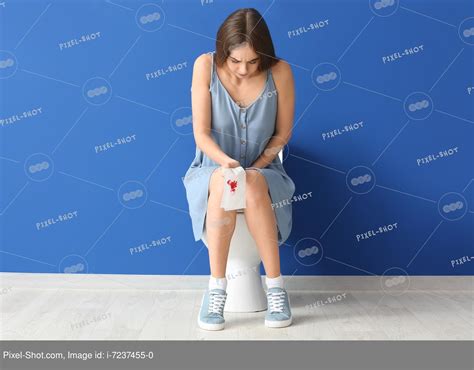 Молодая женщина с геморроем сидит на унитазе в туалете Стоковая