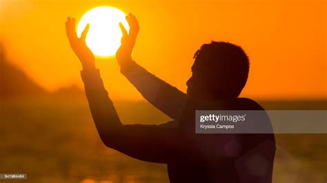 Optical Illusion Of Man Holding Sun At Beach During Sunset High Res