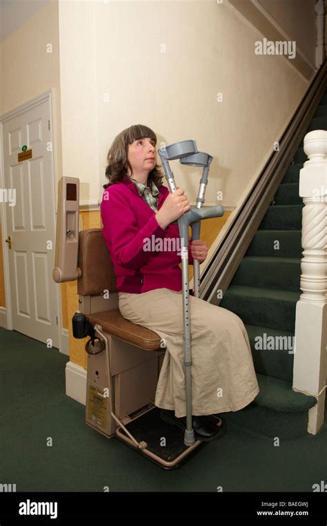 Disabled Amputee Lady In Stair Lift With Crutches In Residential Home