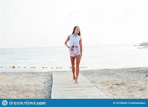 Tanned Woman With Long Hair Walks On Beach By The Sea Stock Photo