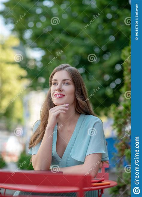 Smiling Cute Female Sitting In Cafe Holding Her Hand Under Chin Stock