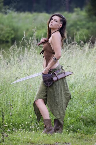 Beautiful Celtic Warrior Woman With Ax And Sword In The Field Stock