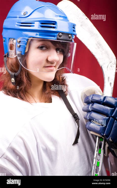 A Girl Hockey Player In Uniform Posing With Helmets Off In Front Of Red