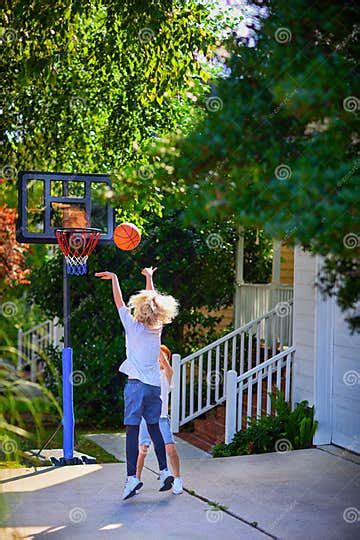 Happy Kids Playing Basketball At The Driveway Of Their Home Portable