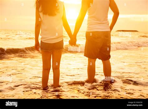 Young Couple Holding Hands At Sunset On Beach Stock Photo Alamy